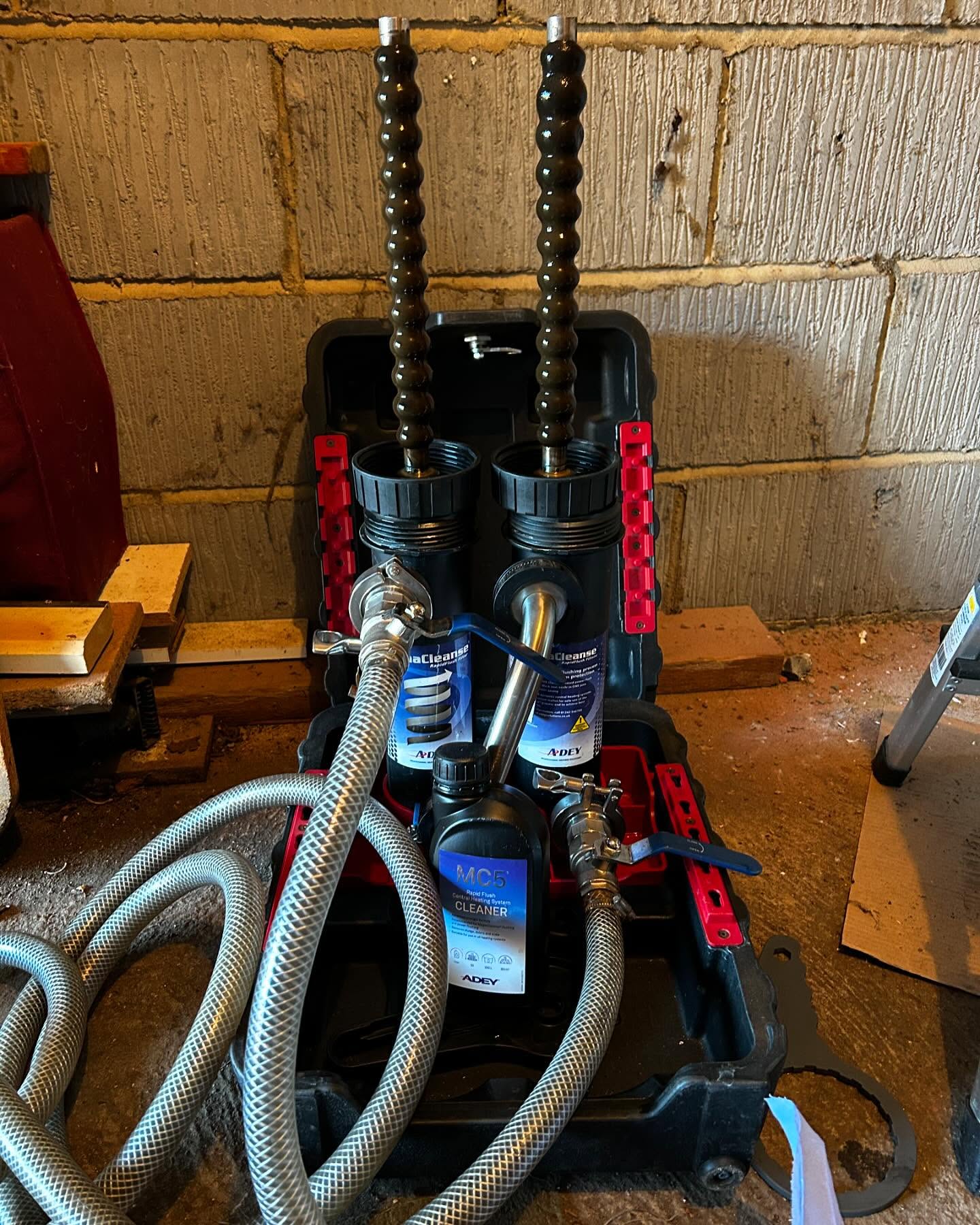 Twin filter housings and hoses set up on a stand against a block wall