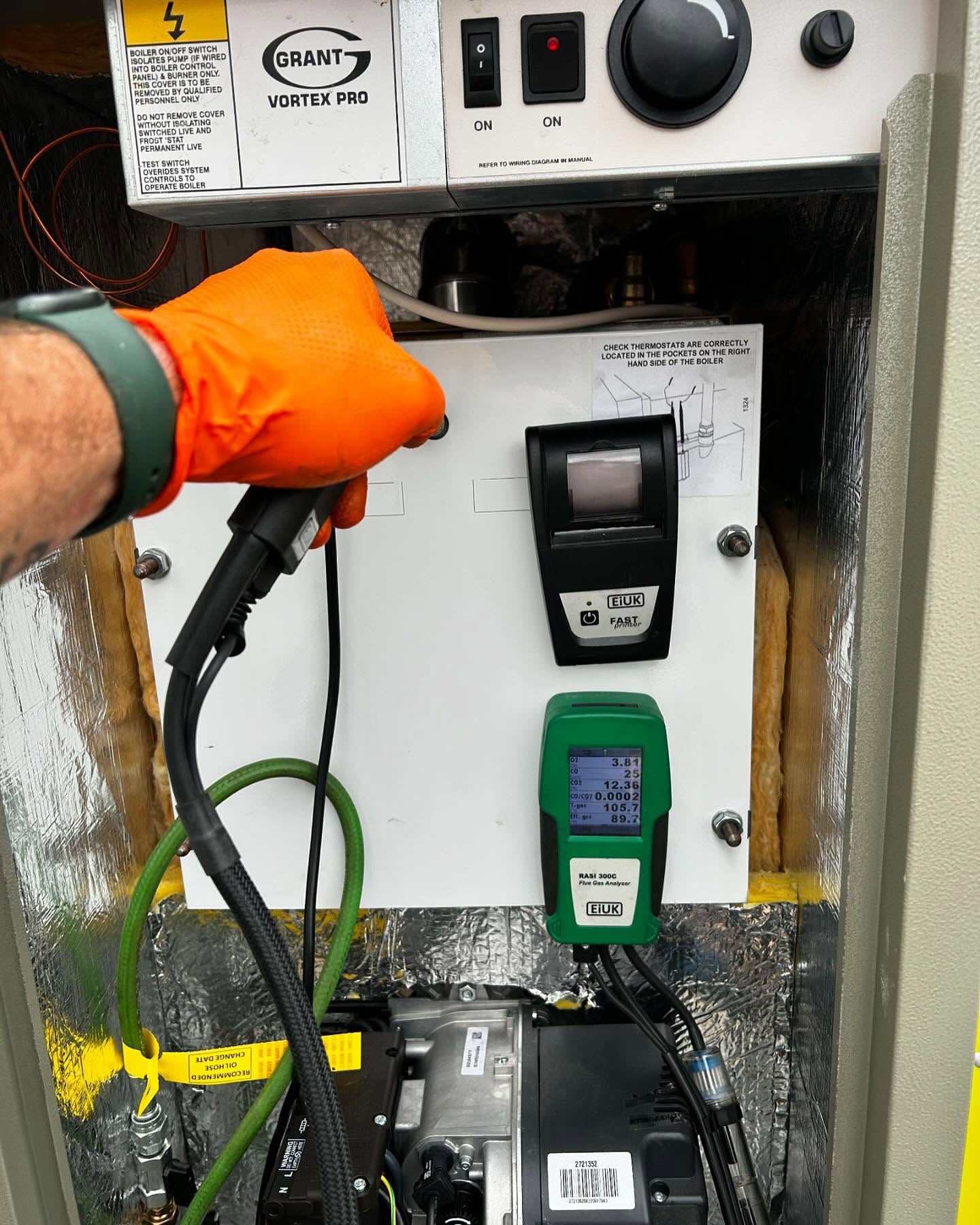 Gloved hand testing an oil boiler with the flue gas analyser probe