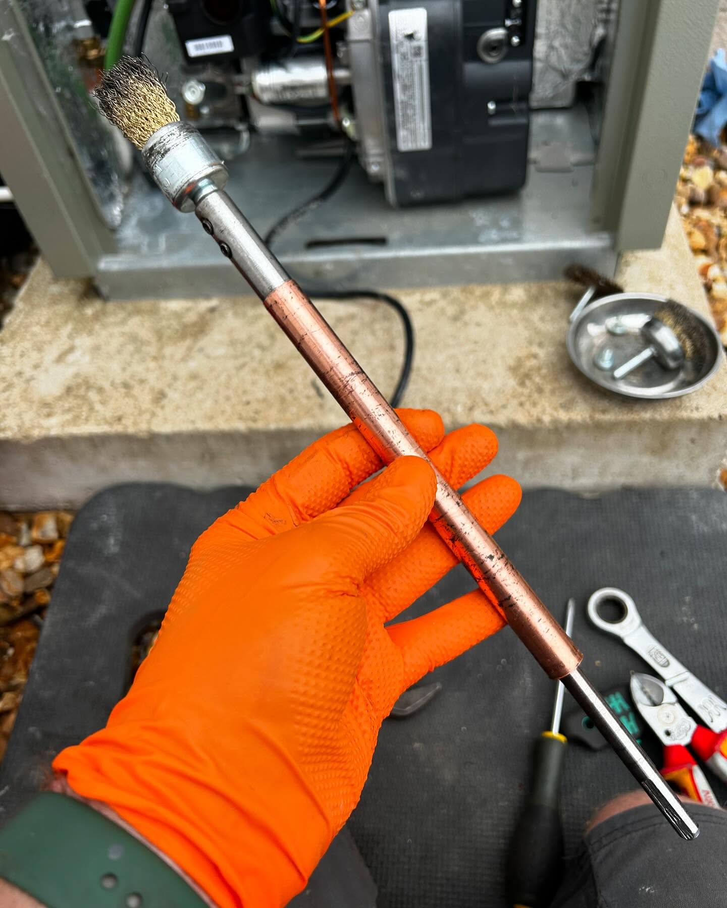 Gloved hand holding a burner assembly during an oil boiler service
