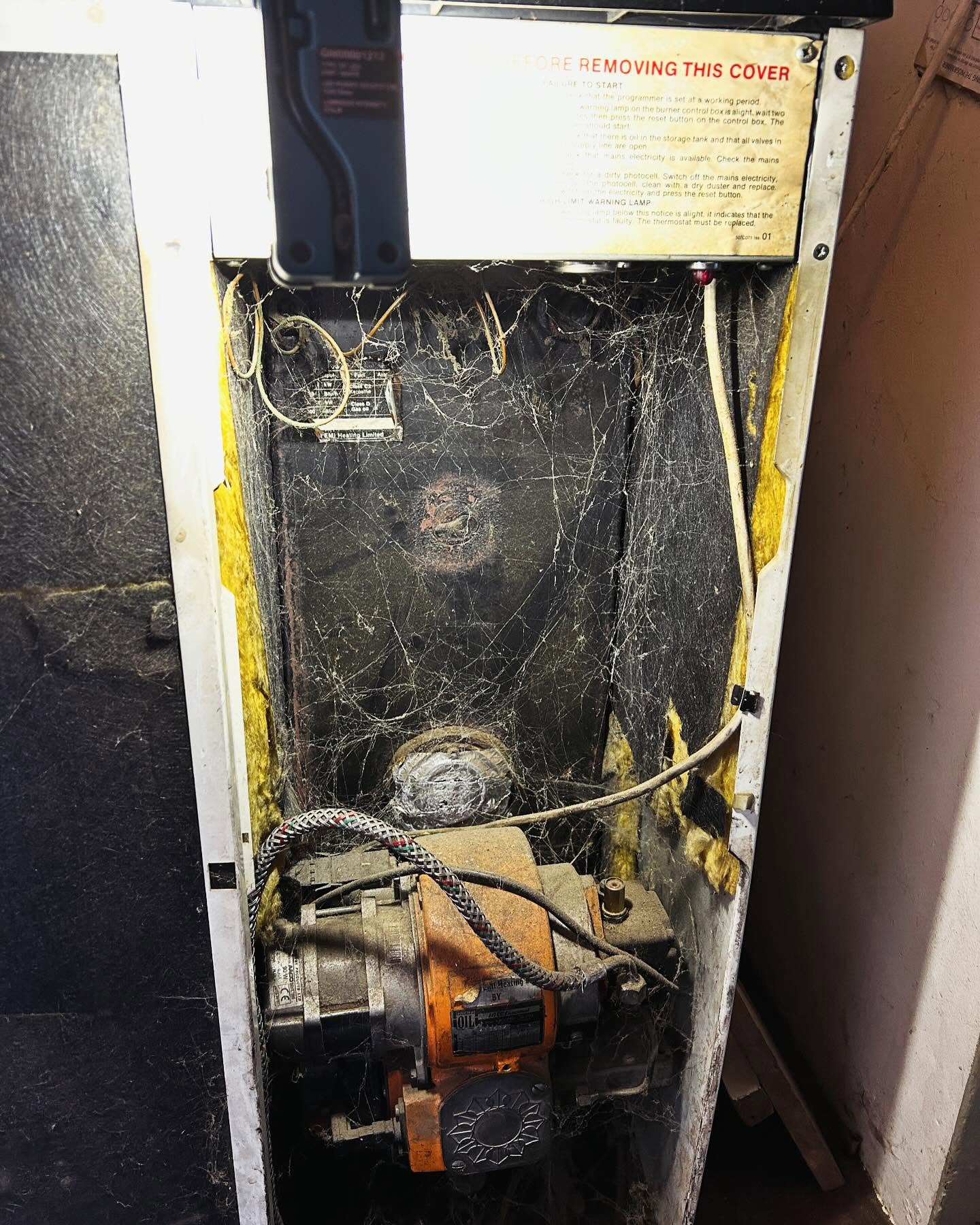 An old floor-standing boiler opened up, full of cobwebs