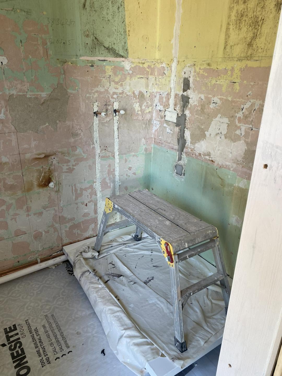 Bathroom stripped back to bare walls with the pipe tails ready