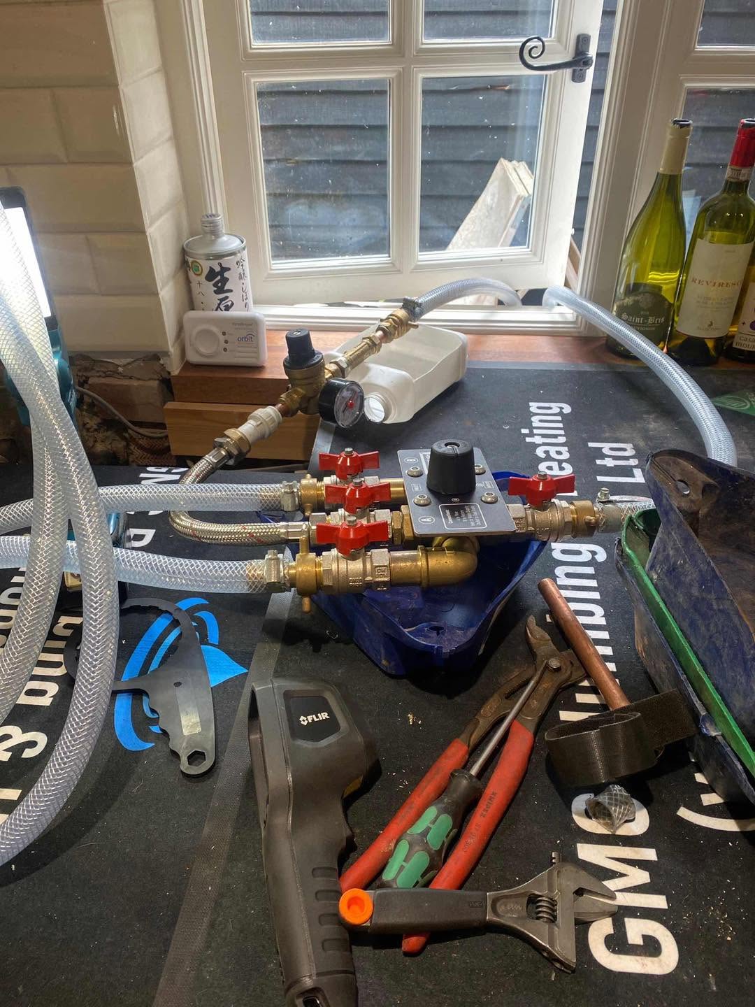 Tools and fittings laid out on a GMC branded mat by a kitchen window