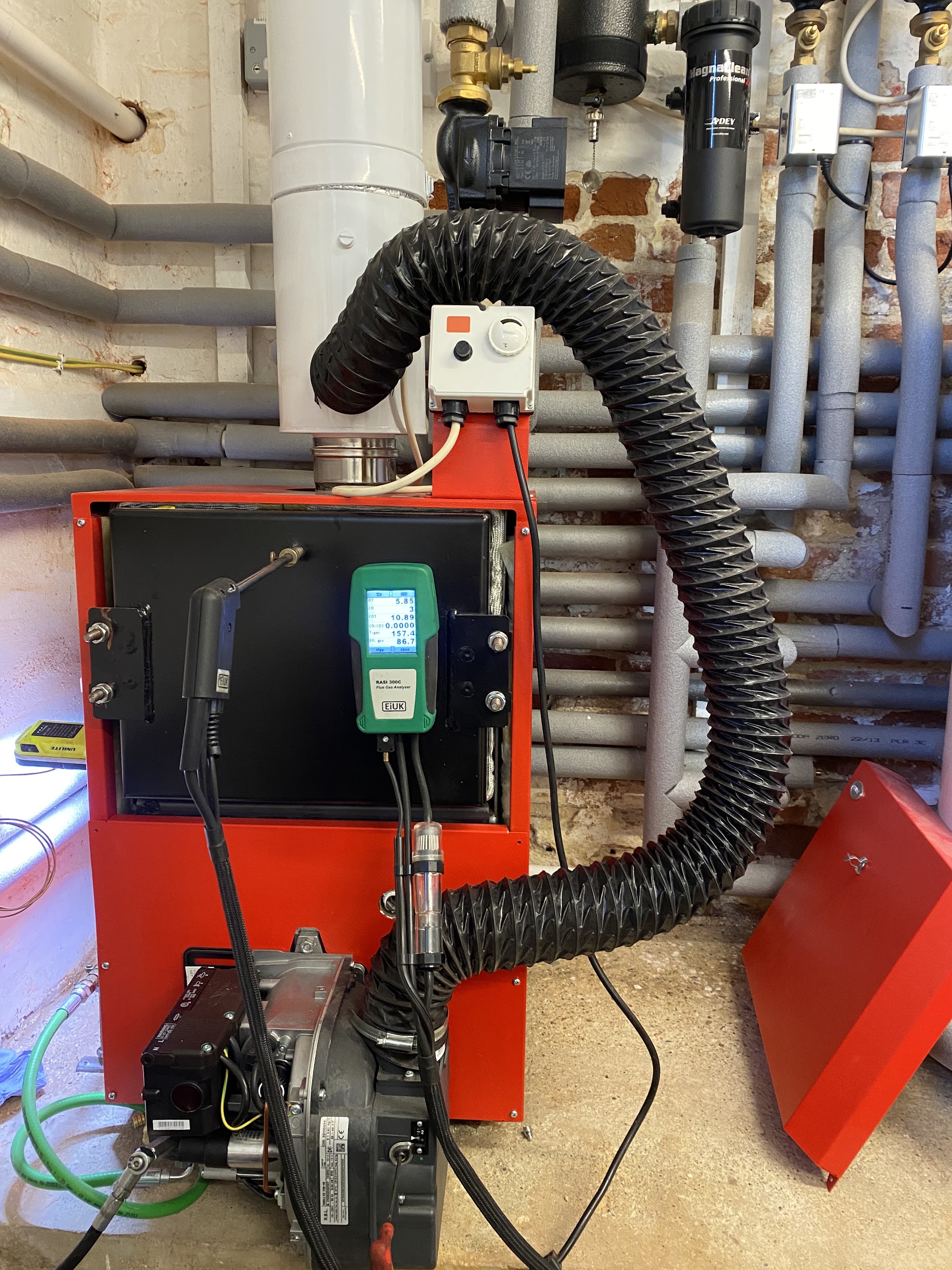 Red oil boiler with its flue hose and the analyser connected during a service