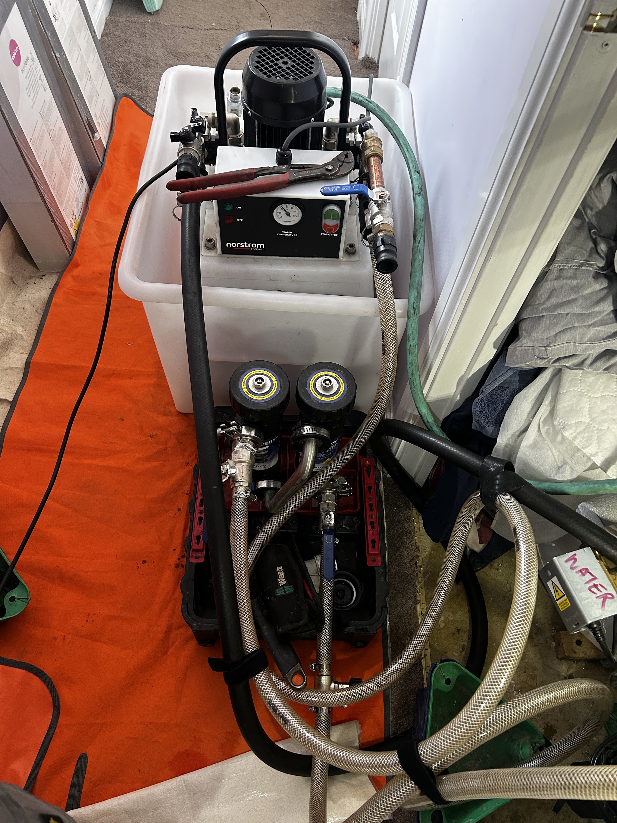 Equipment with a gauge and hoses set up on an orange protective mat